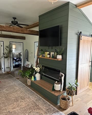 Living room with green shiplap fireplace wall and mounted TV