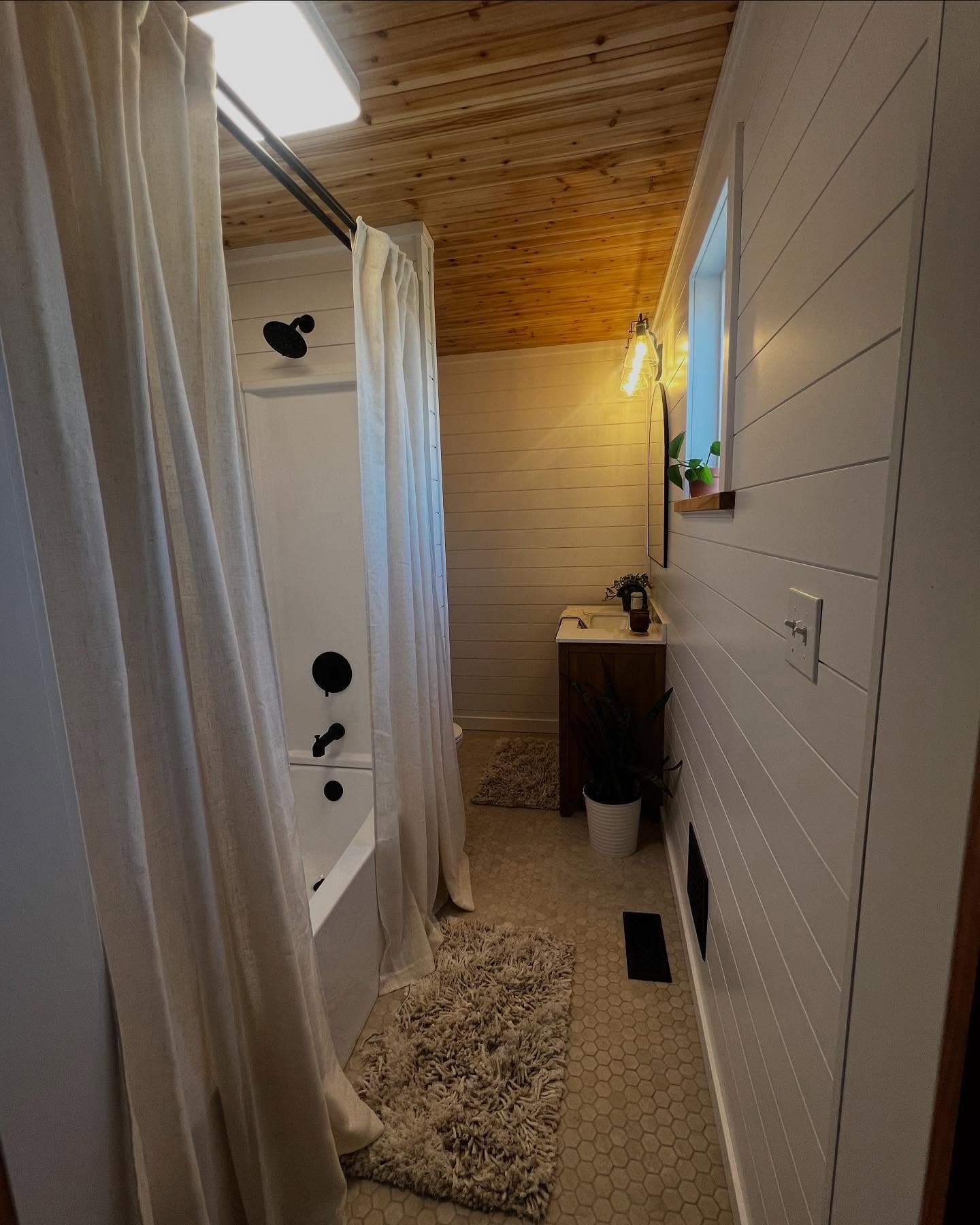 Bathroom with skylight, tub, and wood ceiling