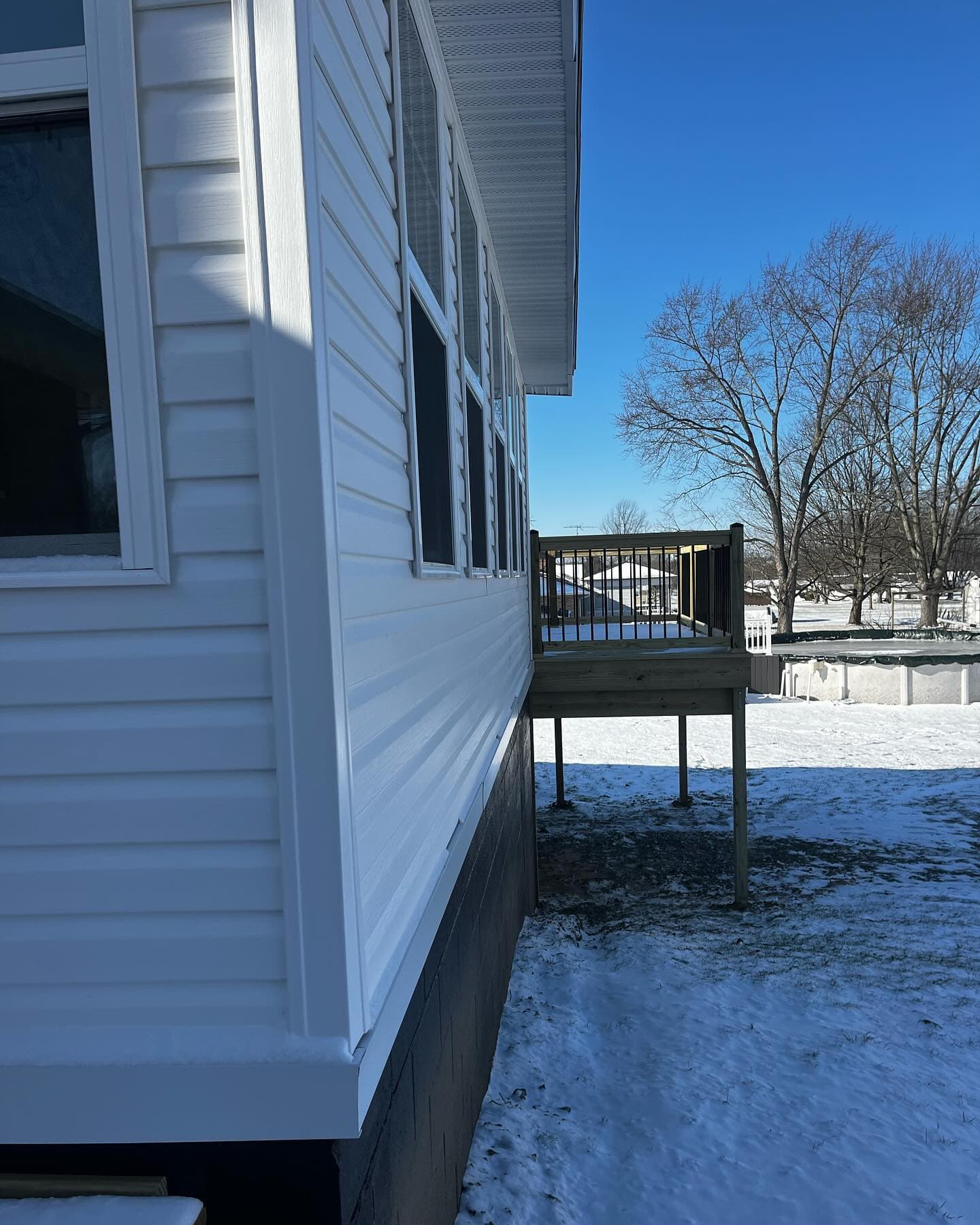 Small new deck with black railings over snow