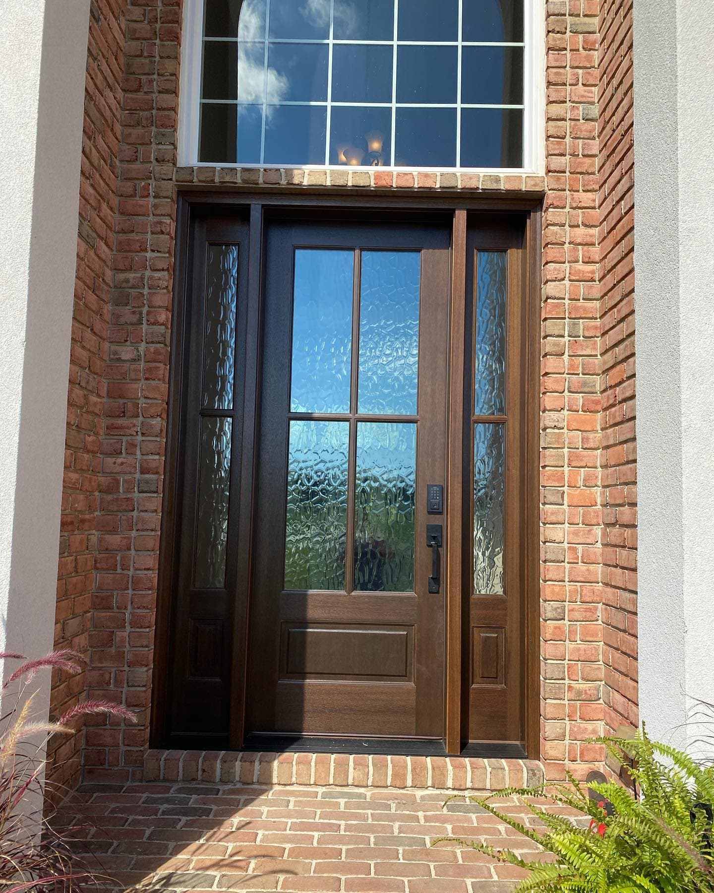 New dark wood entry door with glass panels and brick surround
