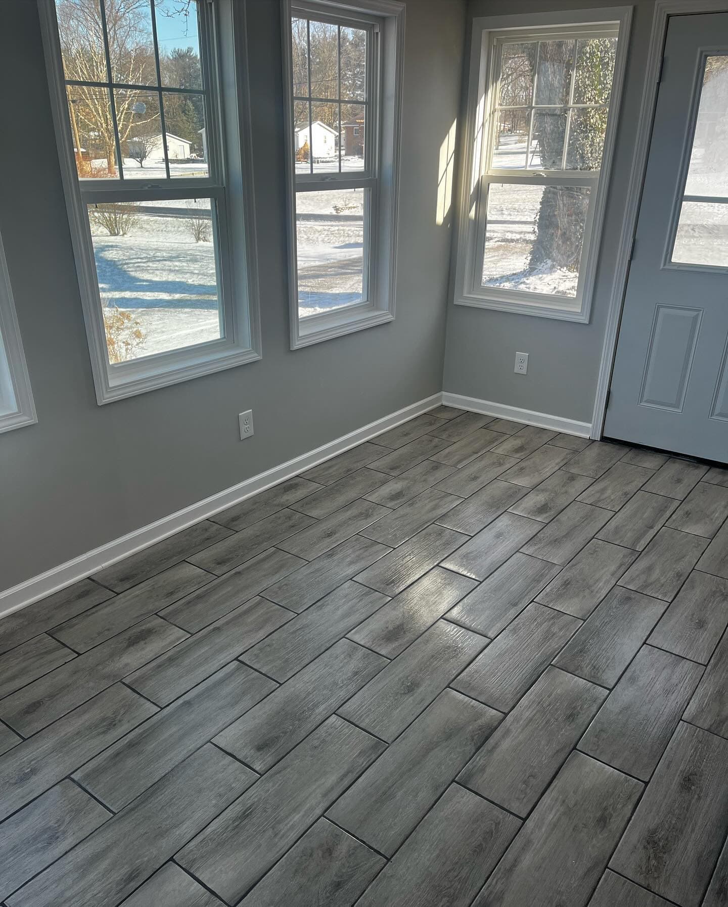 New tile flooring in bright sunroom with large windows