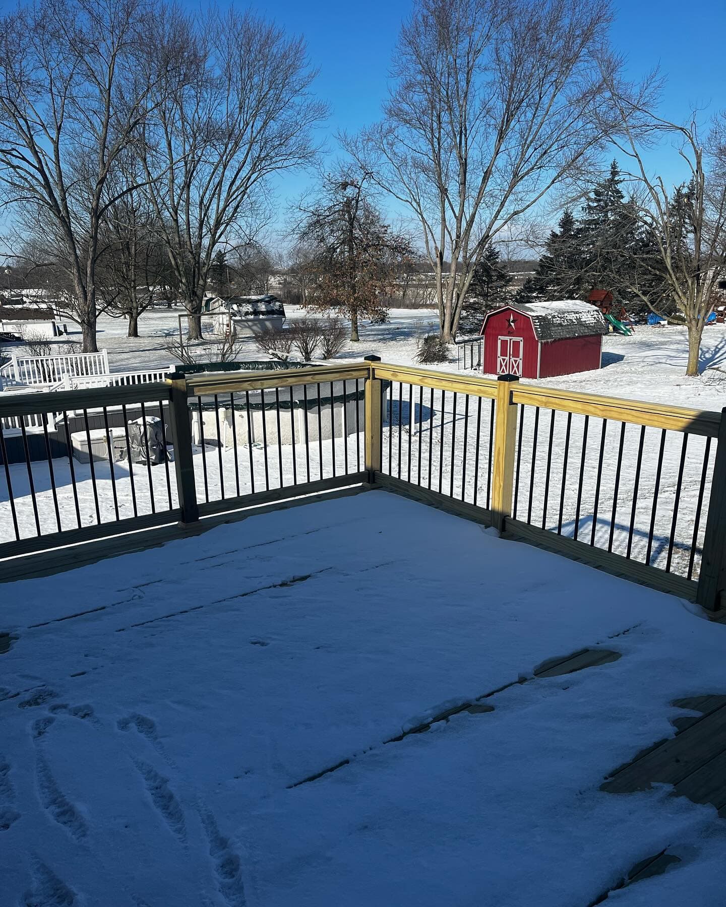 Snow-covered deck with black railings at night