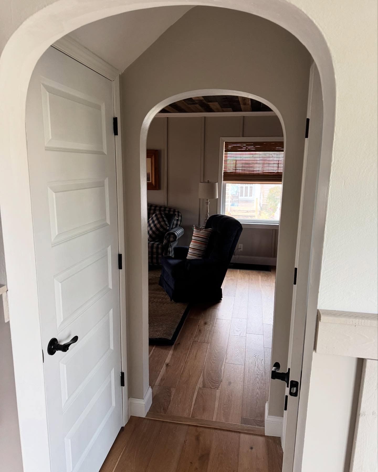 Arched doorway into living room with wood plank ceiling