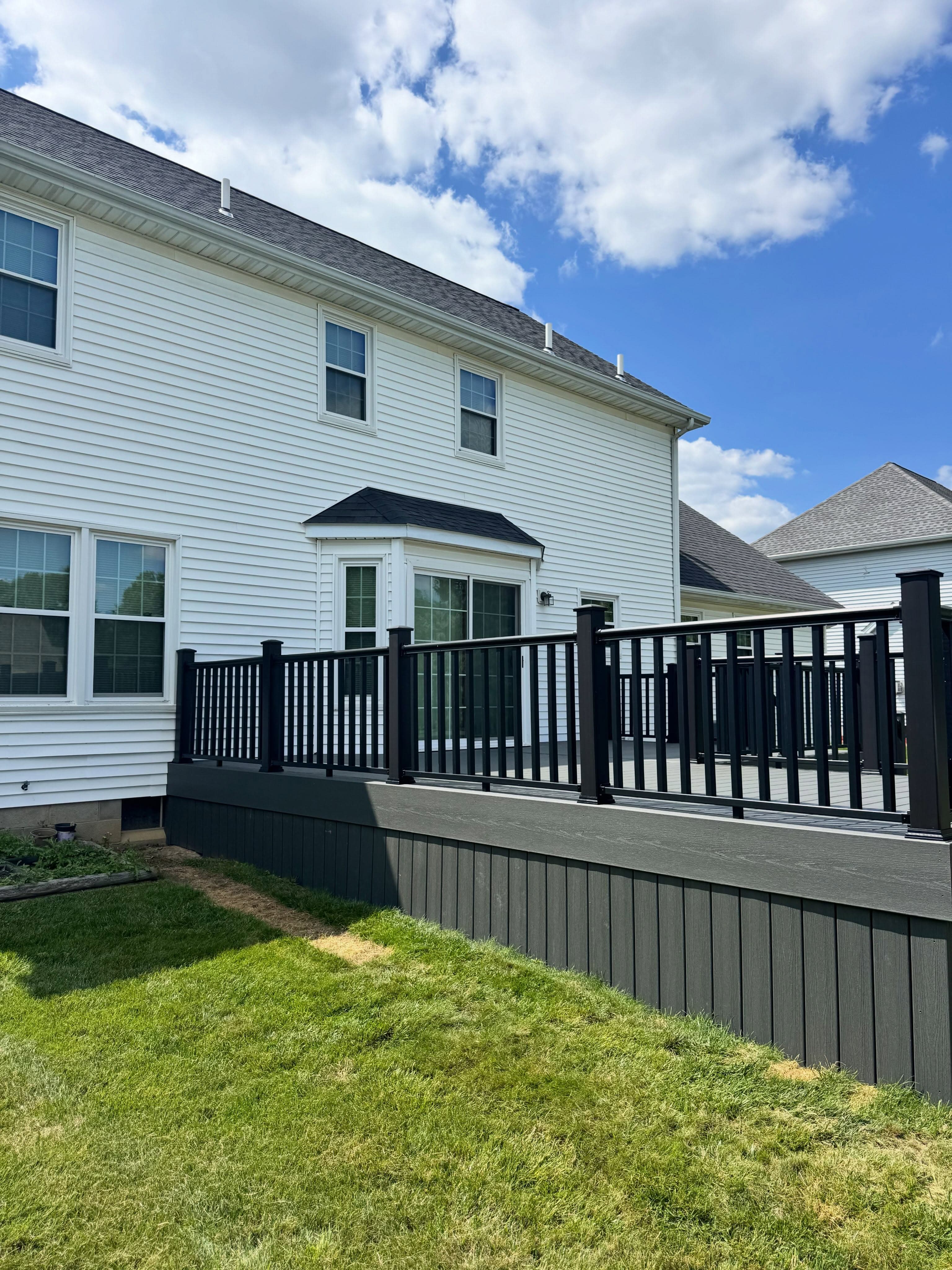Composite deck with black railings on two-story house