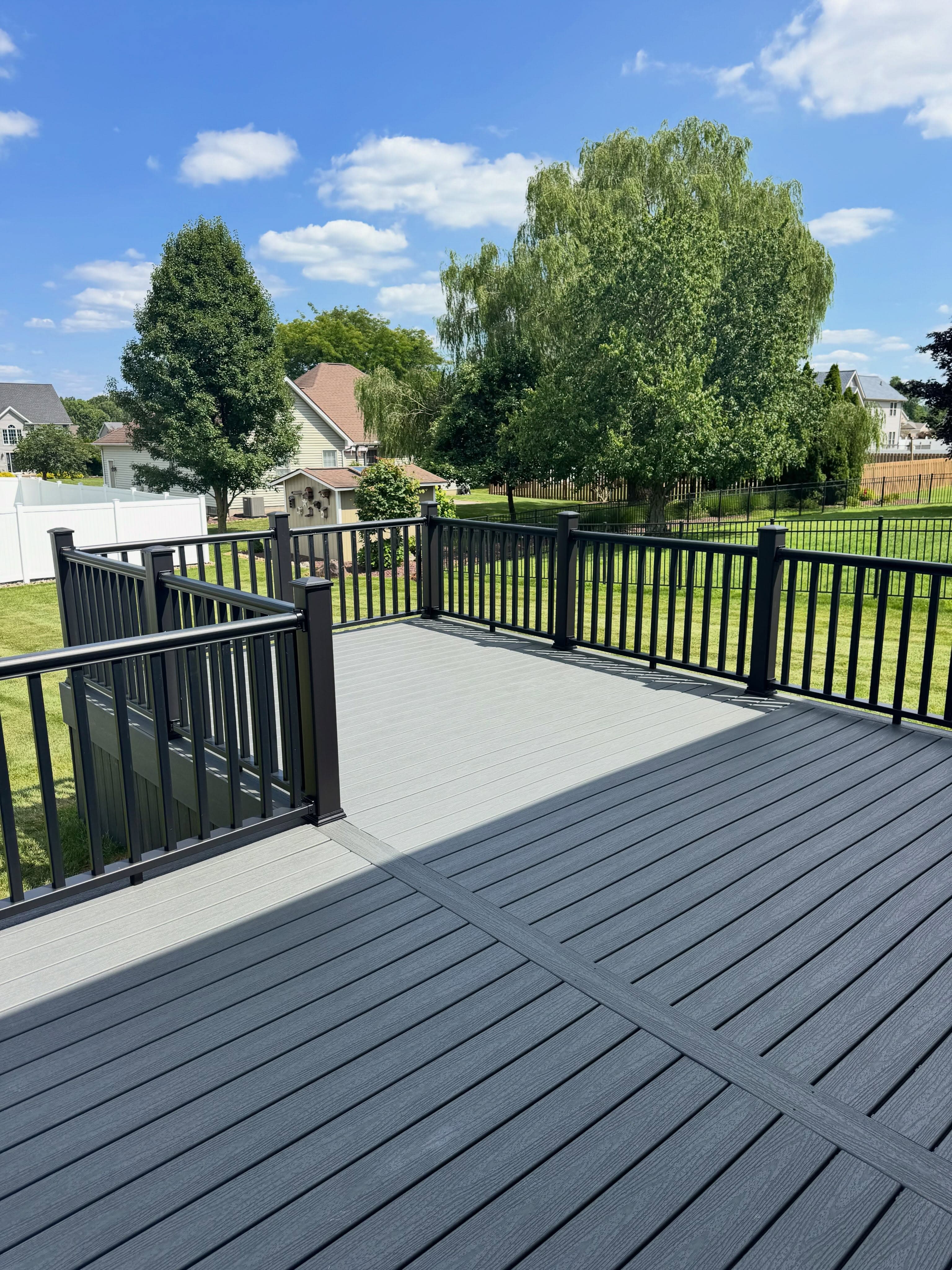 Expansive composite deck with black railings and yard view