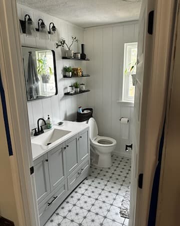 White shiplap bathroom with floating shelves and black vanity
