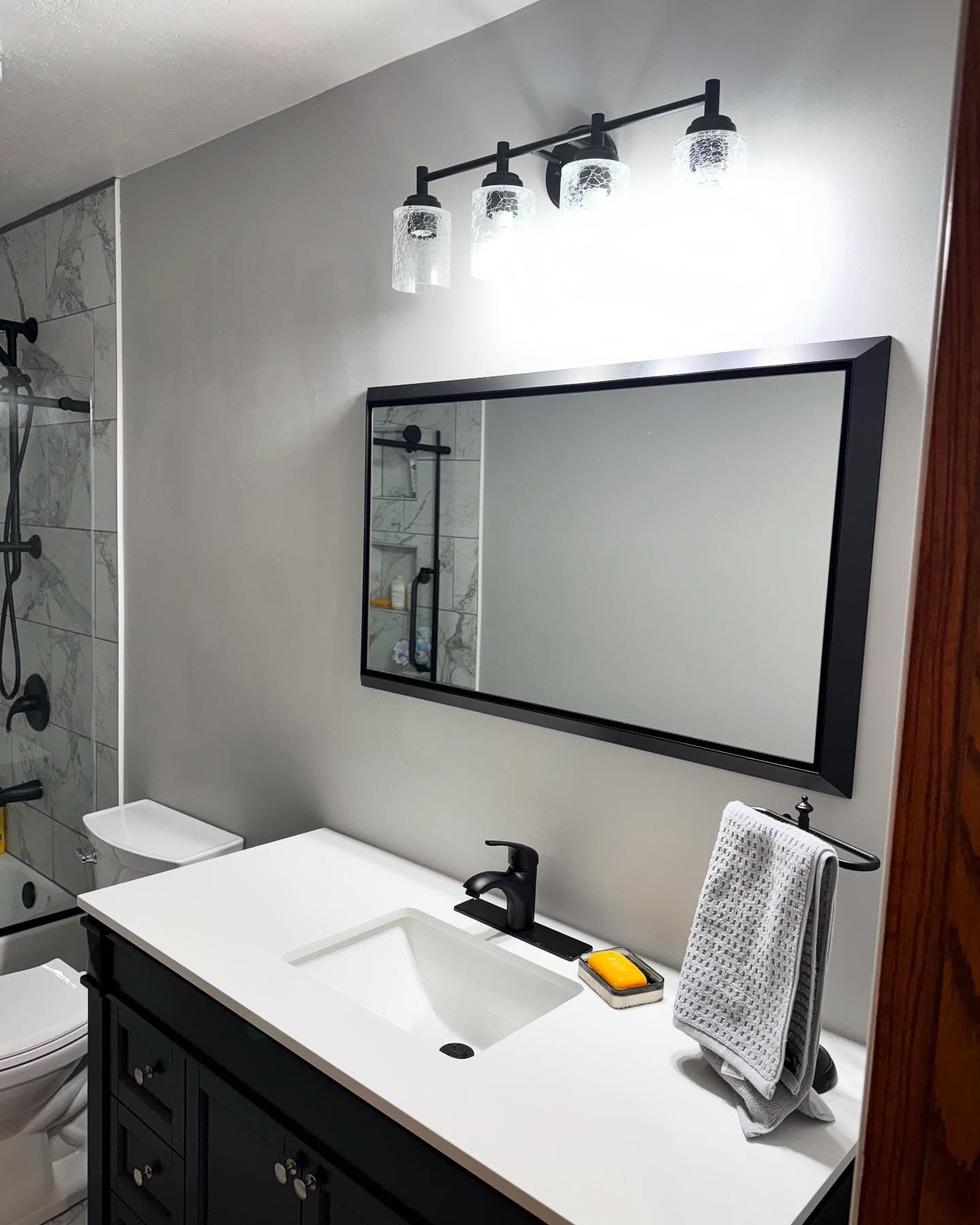 Modern bathroom with black vanity and framed mirror