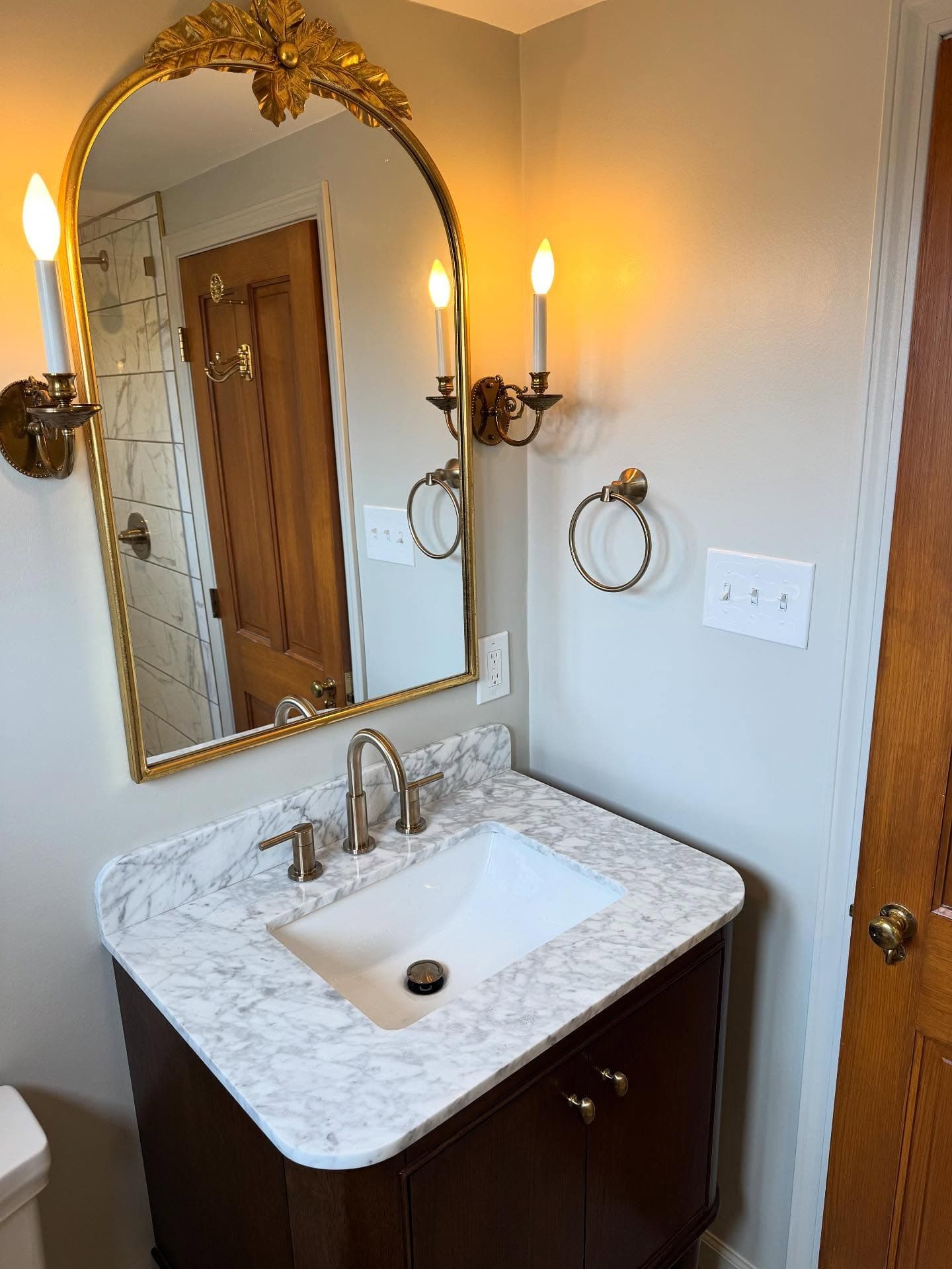 Bathroom vanity corner with brass sconces and towel ring