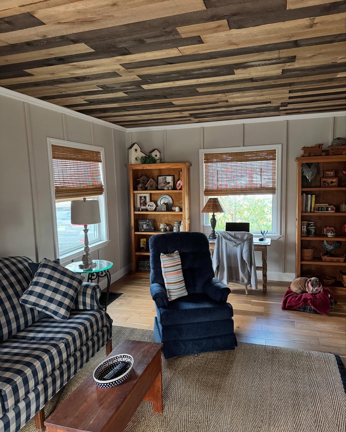 Living room with rustic wood ceiling, bookshelves, and hardwood floor